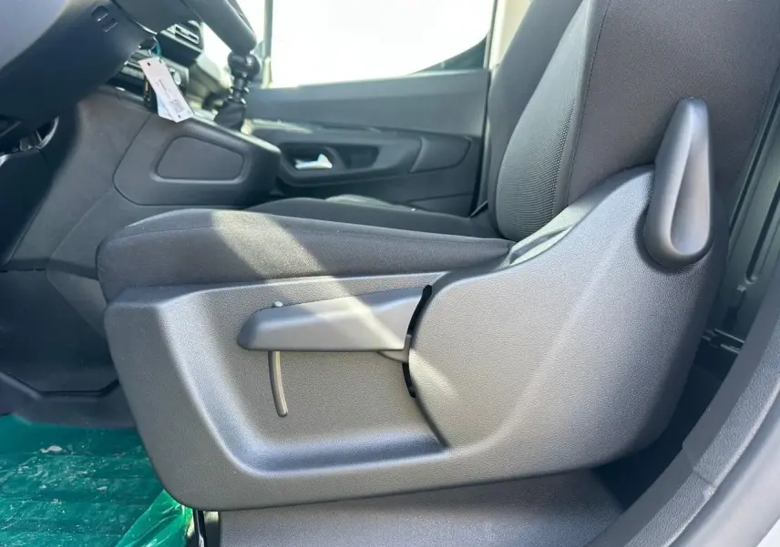 Gros plan sur le siège conducteur tissu gris côté gauche du Citroën Berlingo blanc Icy, avec levier de réglage manuel visible.