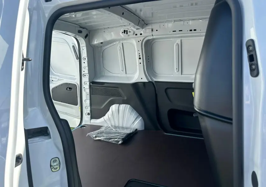 Vue intérieure de la zone de chargement arrière du Citroën Berlingo blanc Icy, avec plancher bois antidérapant et cloison fixe.