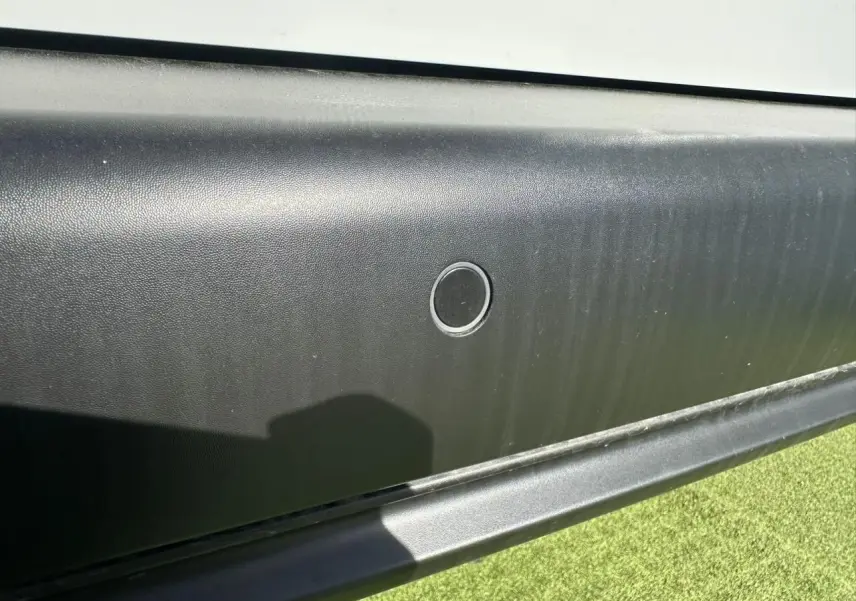 Détail du capteur de stationnement sur la porte latérale droite noire du Citroën Berlingo blanc Icy.