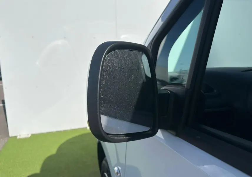 Gros plan sur le rétroviseur noir brillant côté conducteur du Citroën Berlingo blanc Icy, avec partie avant et vitre visible.
