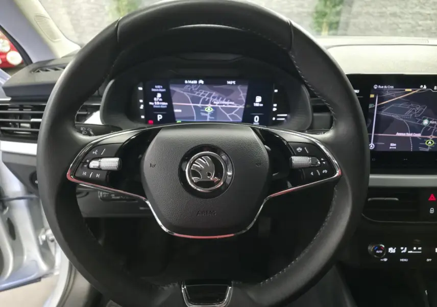 Vue intérieure centrée sur le volant cuir noir du Skoda Kamiq 2023 avec tableau de bord digital et écran de navigation.