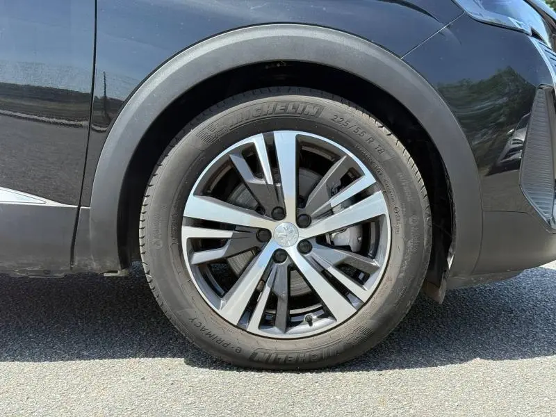 Gros plan sur la roue avant gauche avec jante alu du Peugeot 3008 Hybride Rechargeable noir Perla Nera.