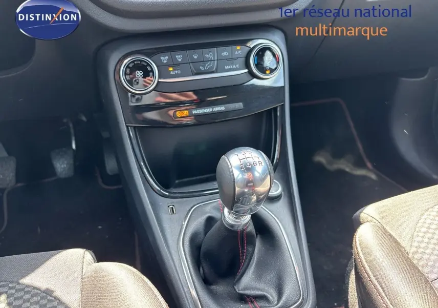 Gros plan sur la console centrale du Ford Puma blanc 2022, mettant en valeur le levier de vitesse manuel et les commandes de climatisation.