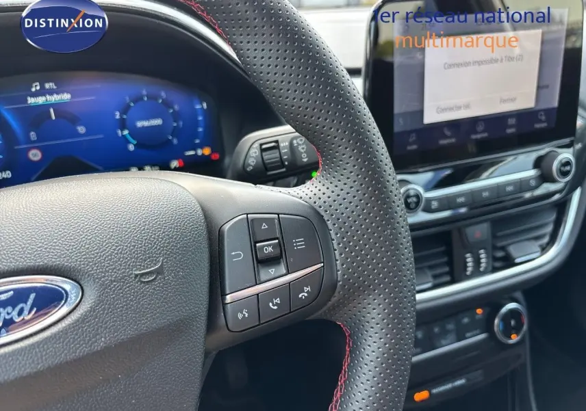 Vue rapprochée du volant perforé avec commandes intégrées et tableau de bord numérique du Ford Puma blanc 2022.