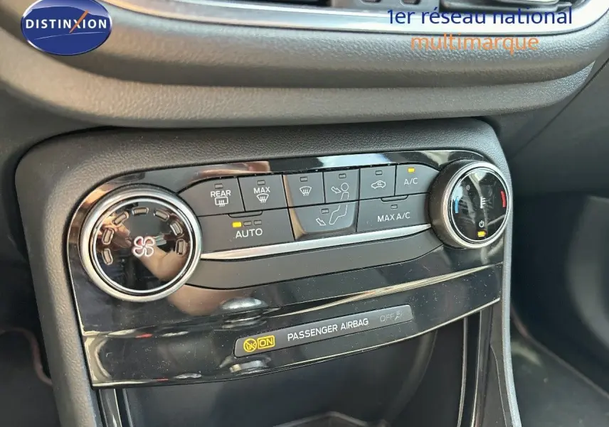Détail de la console centrale du Ford Puma blanc 2022, mettant en valeur les commandes de climatisation et l'indicateur d'airbag passager.