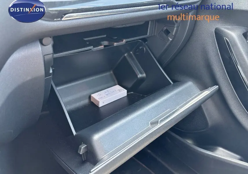 Gros plan sur la boîte à gants ouverte côté passager du Ford Puma blanc, montrant un petit objet posé à l'intérieur.