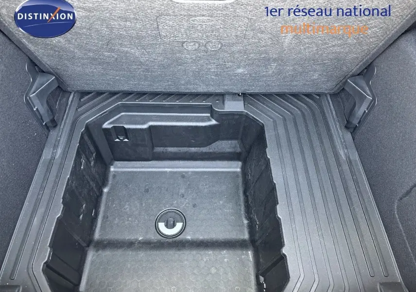 Coffre ouvert montrant le rangement sous plancher en plastique noir du Ford Puma blanc 2022, version hybride essence.