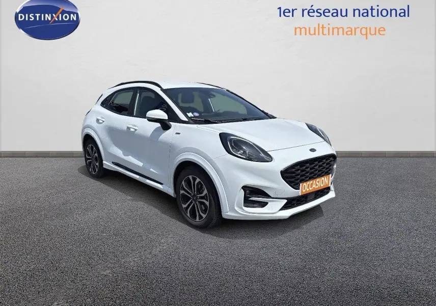 Ford Puma blanc en 3/4 avant droit avec calandre noire et jantes alliage, stationné devant un mur gris.