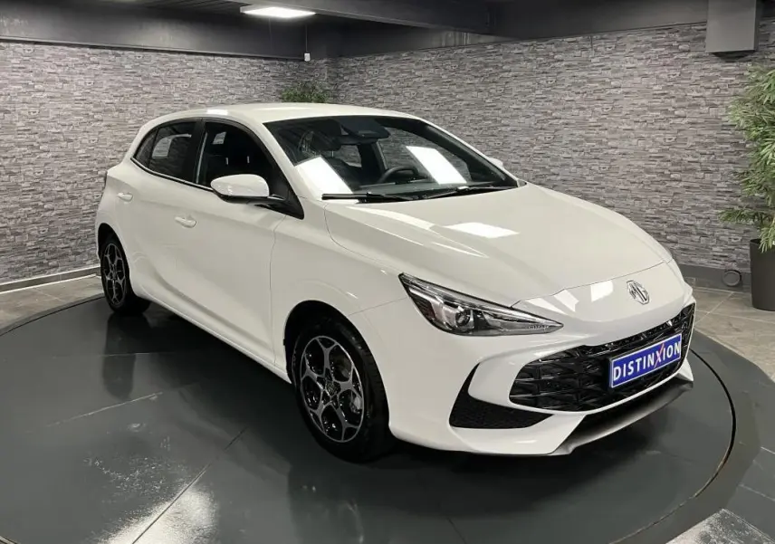 Vue 3/4 avant droite d'une MG3 blanche 2024 avec calandre noire et jantes alliage distinctives en intérieur showroom.