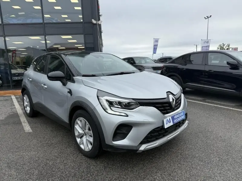 Renault Captur E-Tech 145 Zen gris métal en 3/4 avant droit, avec calandre noire et feux LED distinctifs.