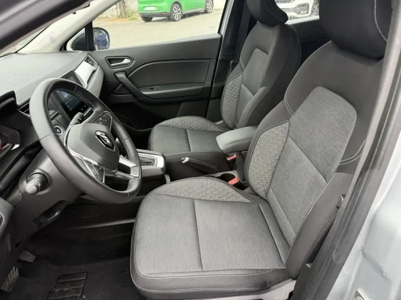 Intérieur avant du Renault Captur E-Tech 145 Zen 2022 gris métal, sièges tissu gris et volant multifonction visible côté conducteur.