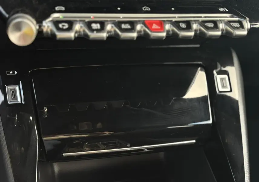 Gros plan sur la console centrale noire brillante du Peugeot 2008 Hybrid 145 e-DSC6 Allure, avec commandes tactiles et ports USB-C.