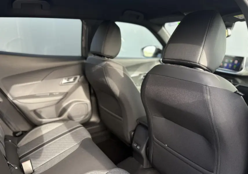 Vue intérieure arrière du Peugeot 2008 Hybrid 145 e-DSC6 Allure 2025, sièges tissu noir et gris, habitacle lumineux.