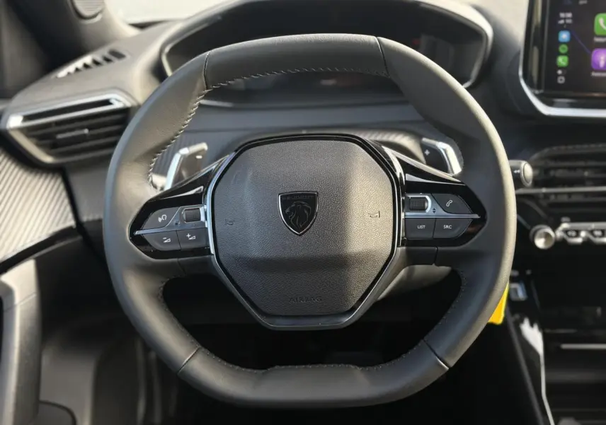 Vue rapprochée du volant compact en cuir noir avec commandes multimédia du Peugeot 2008 Hybrid 145 e-DSC6 Allure.