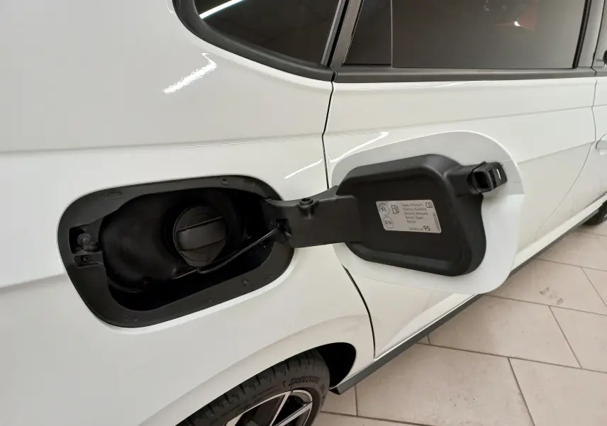 Vue rapprochée côté gauche arrière d'une Volkswagen Polo blanche avec toit noir, trappe à carburant ouverte montrant le bouchon.