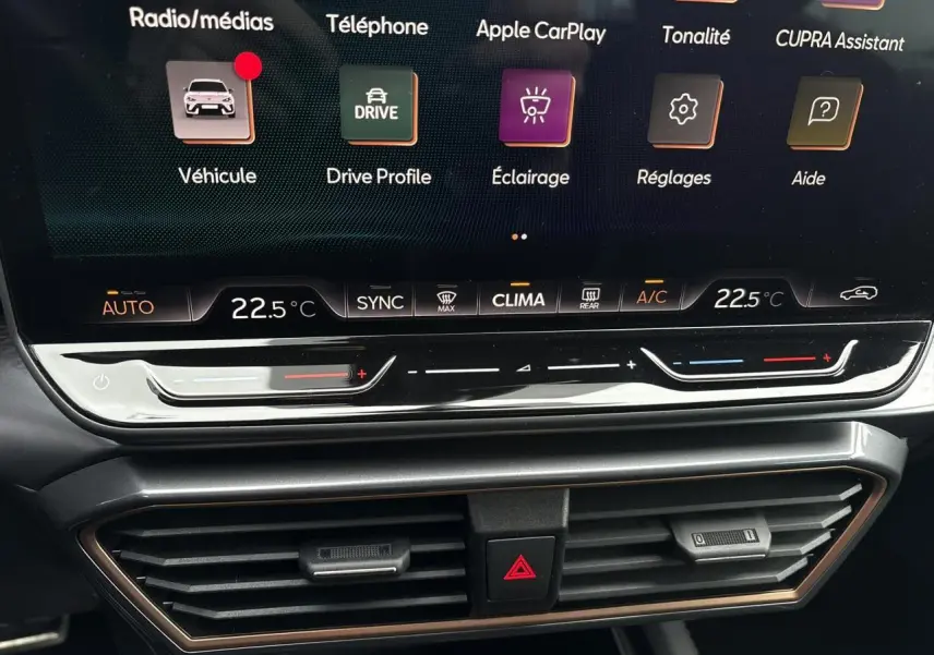 Gros plan sur l'écran tactile et la commande de climatisation du tableau de bord de la CUPRA Leon ST gris Graphene.