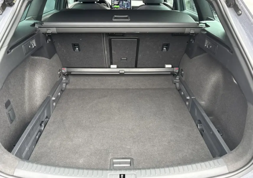 Vue intérieure du coffre spacieux de la CUPRA LEON ST 2025 en Gris Graphene, avec banquette arrière et tablette tactile visibles.