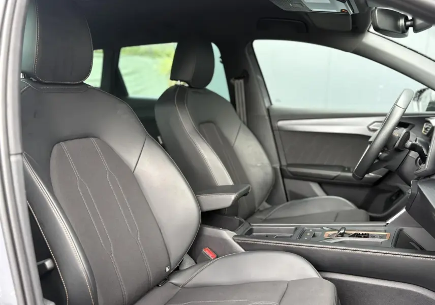 Vue intérieure côté conducteur de la CUPRA LEON ST 2025, sièges cuir noir avec surpiqûres contrastées et console centrale.