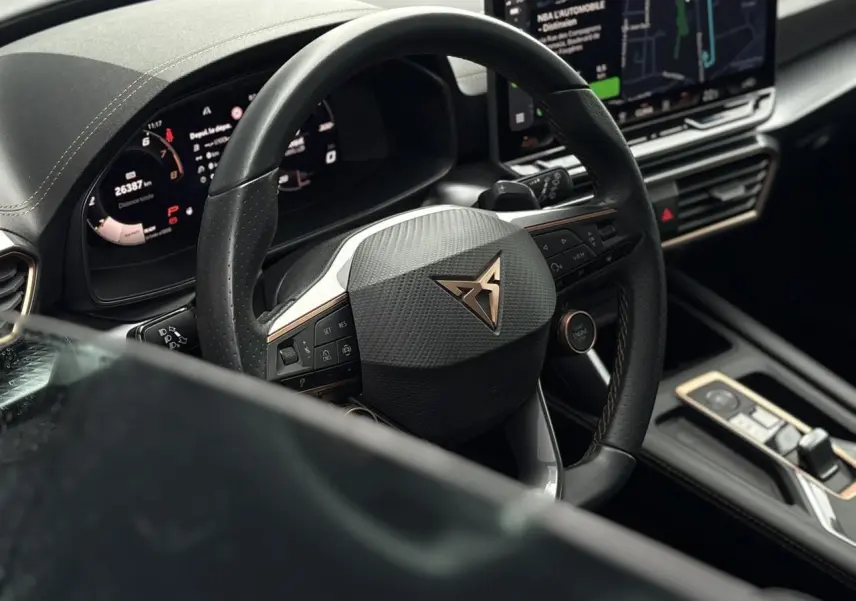 Vue rapprochée du volant noir avec logo CUPRA cuivré et tableau de bord numérique d'une CUPRA LEON ST 2025.