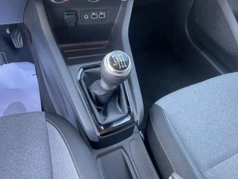 Gros plan sur le levier de vitesse manuel noir de la Renault Clio V DCI 100 Evolution 2025, intérieur gris et noir.