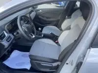 Vue intérieure côté conducteur de la Renault Clio V DCI 100 Evolution 2025, sièges gris clair et volant multifonction.