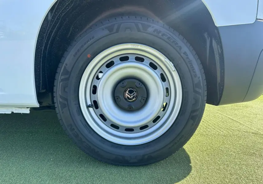Gros plan sur la roue arrière droite en jante tôle grise du Citroën Berlingo blanc Icy, avec partie basse de la carrosserie visible.
