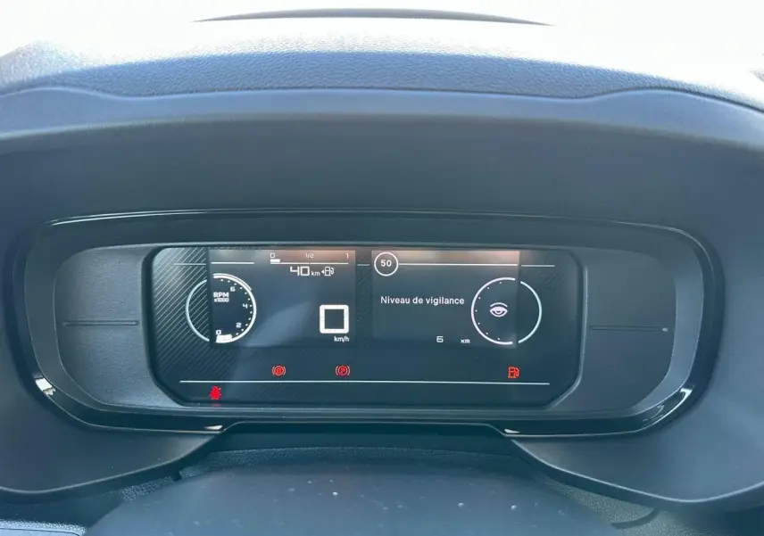 Vue rapprochée du tableau de bord numérique du Citroën Berlingo blanc, affichant la vitesse et le niveau de vigilance.