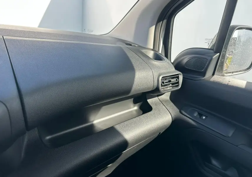 Détail de l’intérieur côté passager du Citroën Berlingo blanc, montrant la planche de bord et la grille d’aération.