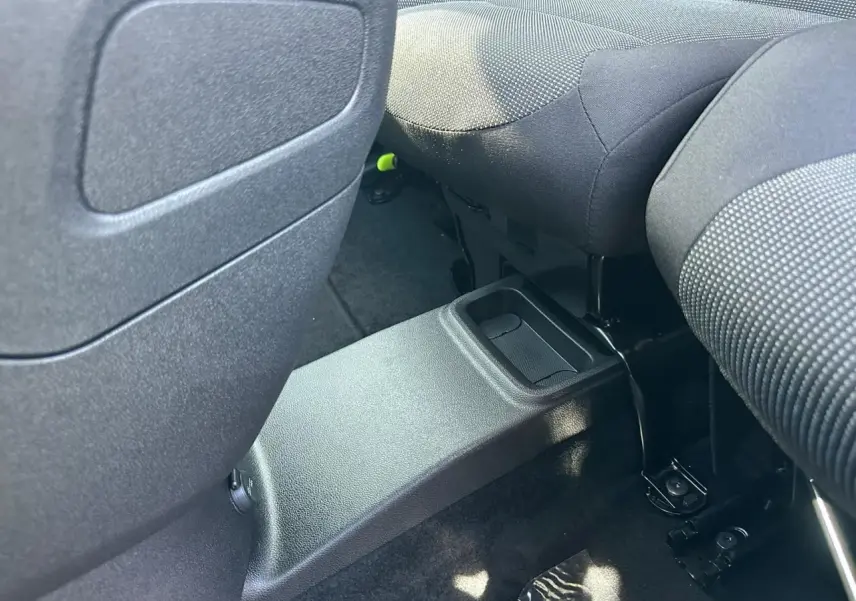 Vue rapprochée de l'espace entre les sièges arrière noirs du Citroën Berlingo III blanc, avec console centrale basse.