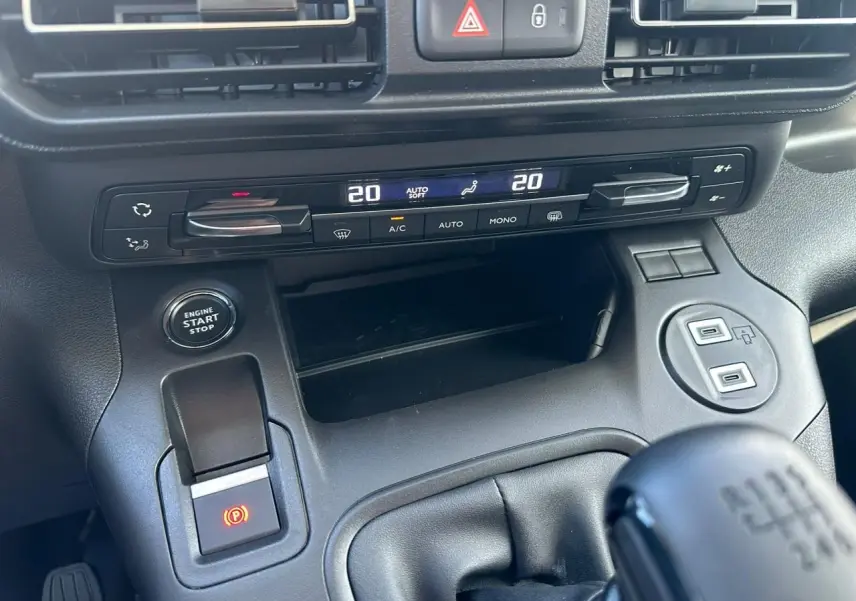 Vue rapprochée de la console centrale noire du Citroën Berlingo blanc, avec commandes climatisation et bouton start/stop.