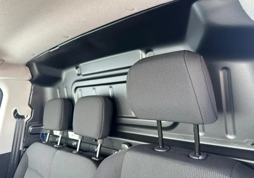 Vue intérieure sur la banquette passager noire avec appuis-tête, cloison métallique arrière du Citroën Berlingo blanc.