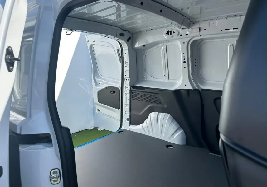 Vue intérieure de la zone de chargement du Citroën Berlingo blanc Icy, avec porte latérale droite ouverte et plancher plat.