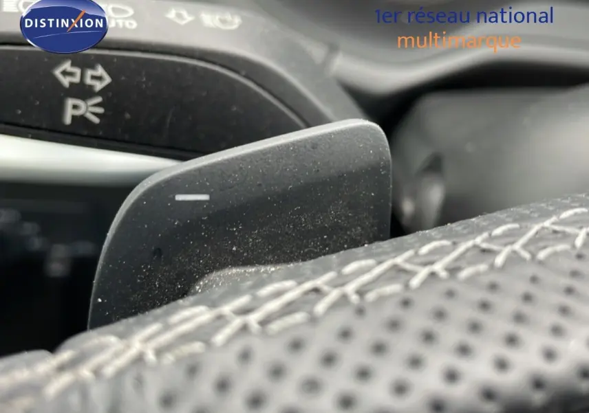 Gros plan sur la palette de changement de vitesse derrière le volant en cuir perforé d’un Audi Q2 noir mito metal.