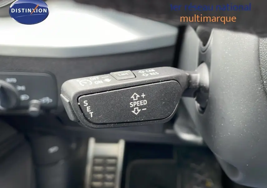 Gros plan sur la commande de régulateur de vitesse au volant d’un Audi Q2 noir mito metal, intérieur noir.