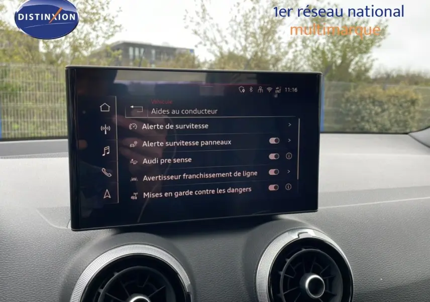 Écran tactile central affichant les aides à la conduite dans l'habitacle d'un Audi Q2 noir, vue intérieure avant.