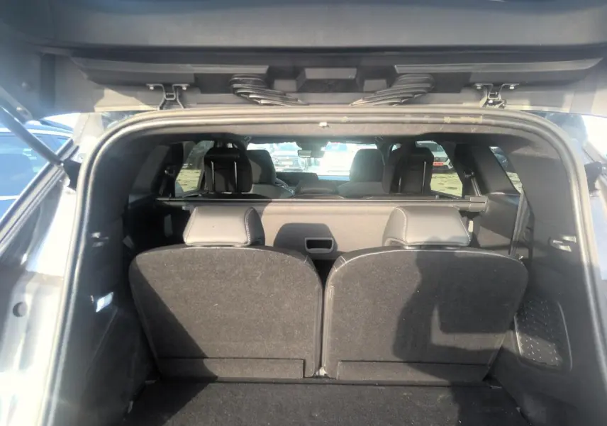 Vue arrière du coffre ouvert d’un Peugeot 5008 gris foncé, montrant les sièges arrière relevés et l’habitacle intérieur.
