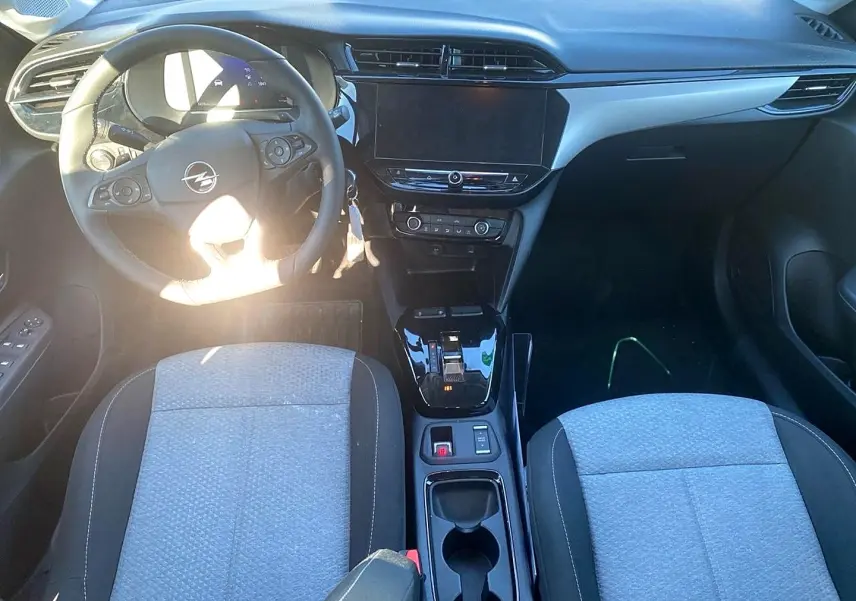 Vue intérieure avant de l’Opel Corsa 1.2 turbo 2025, tableau de bord noir avec écran tactile et sièges tissu gris.