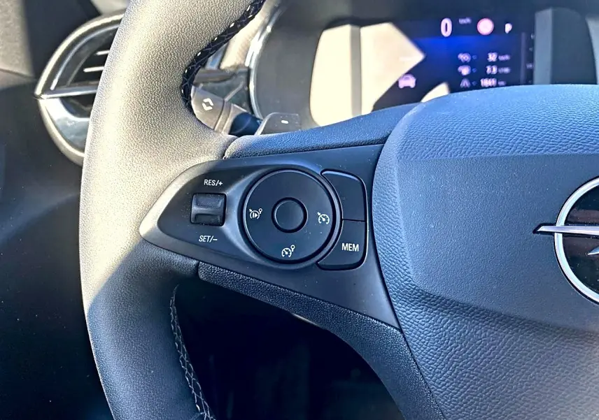 Gros plan sur le côté gauche du volant noir de l'Opel Corsa 2025 avec commandes de régulateur de vitesse.