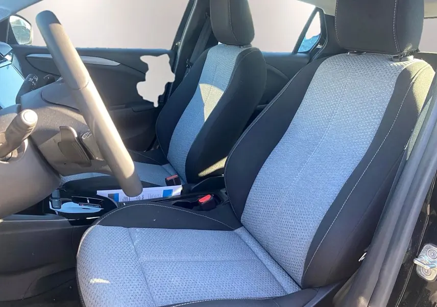 Vue intérieure côté conducteur de l’Opel Corsa noir 2025, sièges tissu bicolore gris et noir avec volant multifonction.