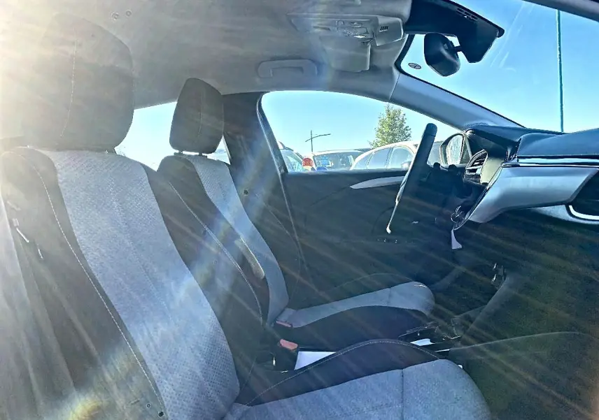 Vue intérieure côté conducteur de l’Opel Corsa 2025, sièges tissu noir et gris avec volant multifonction sport visible.