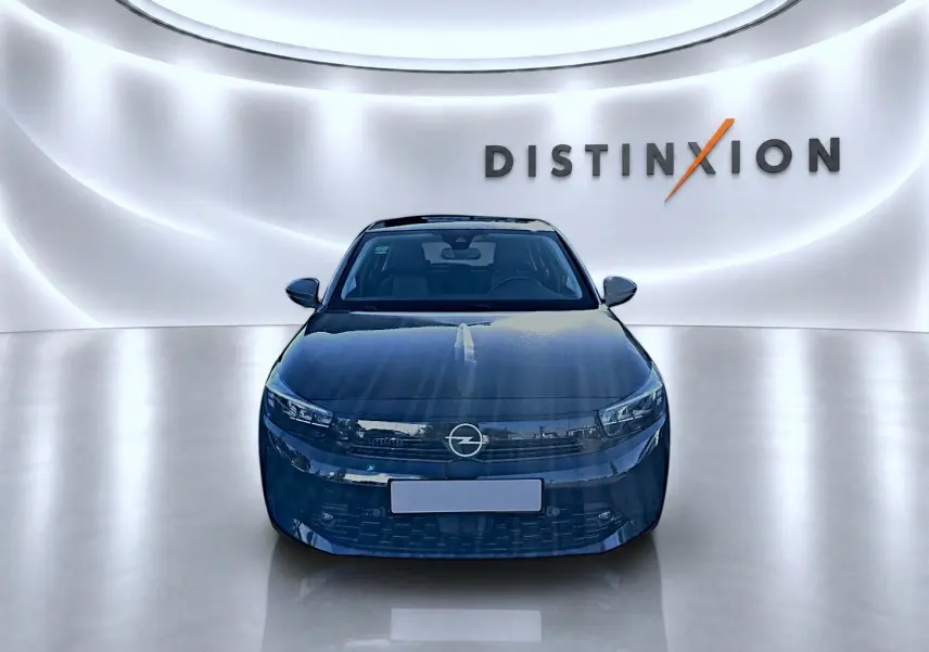 Vue frontale d'une Opel Corsa noire 2025 dans un showroom avec un mur lumineux marqué Distinxion.