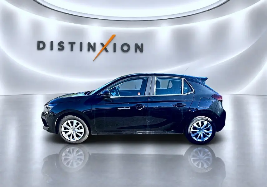 Opel Corsa noire vue de profil côté gauche, avec jantes alliage et becquet arrière en showroom lumineux.