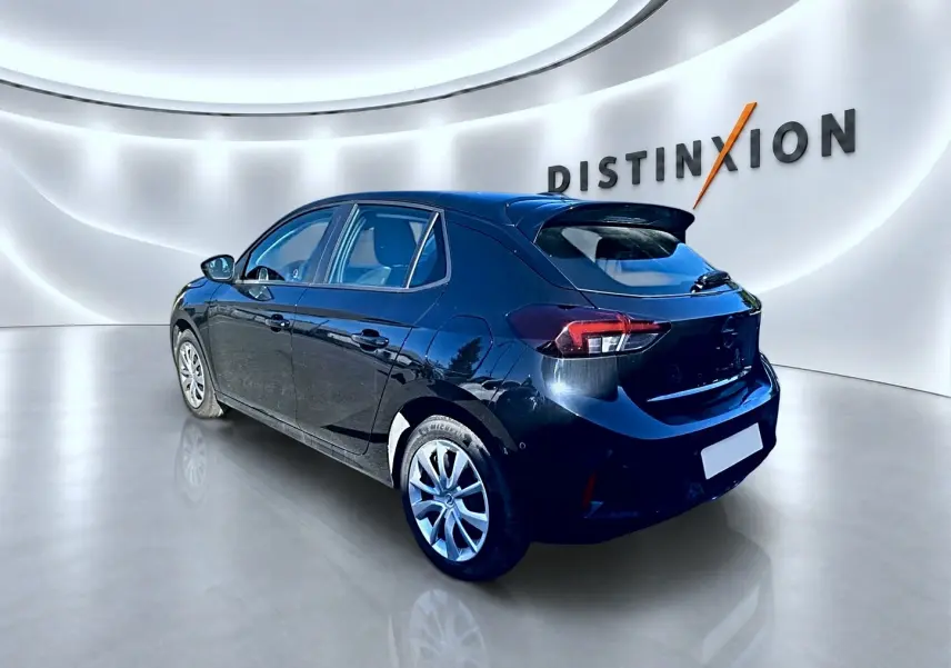 Opel Corsa noire vue 3/4 arrière droit dans un showroom lumineux avec becquet et jantes alliage.