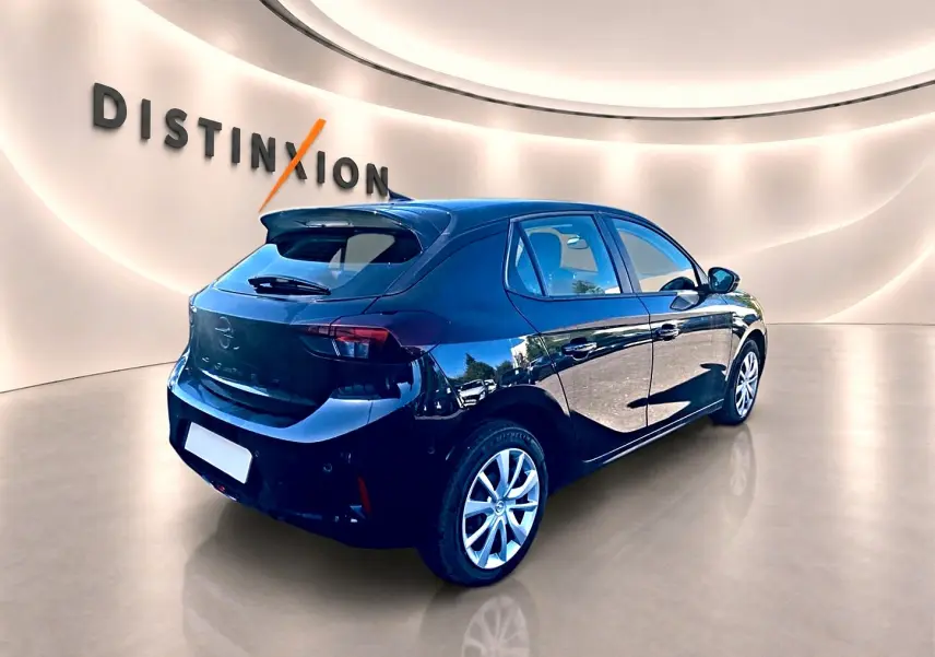 Opel Corsa noire vue 3/4 arrière droit dans un showroom avec becquet et jantes alliage visibles.