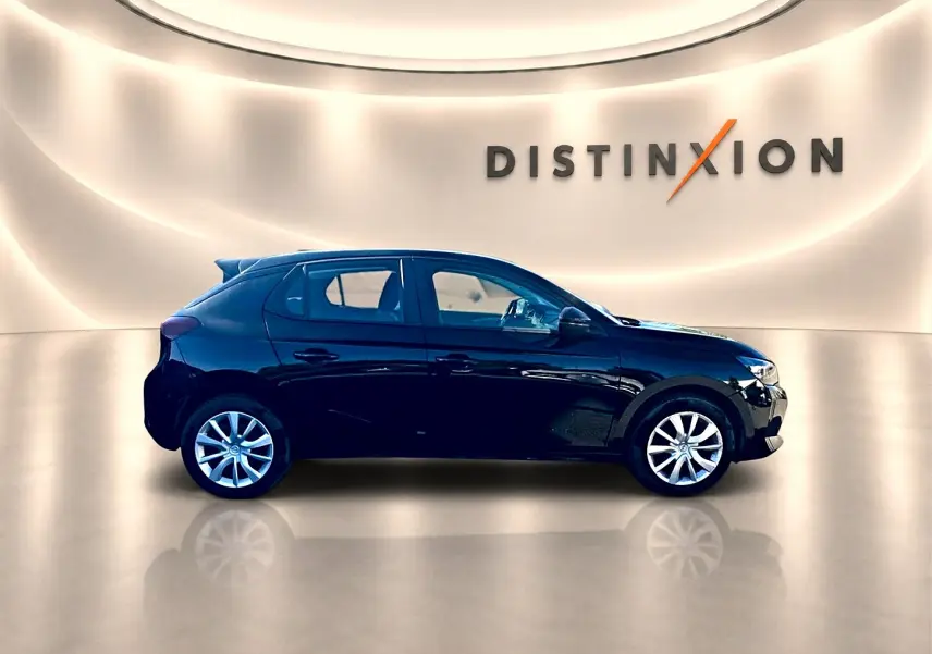 Opel Corsa noire vue de profil côté gauche dans un showroom lumineux avec logo Distinxion en arrière-plan.