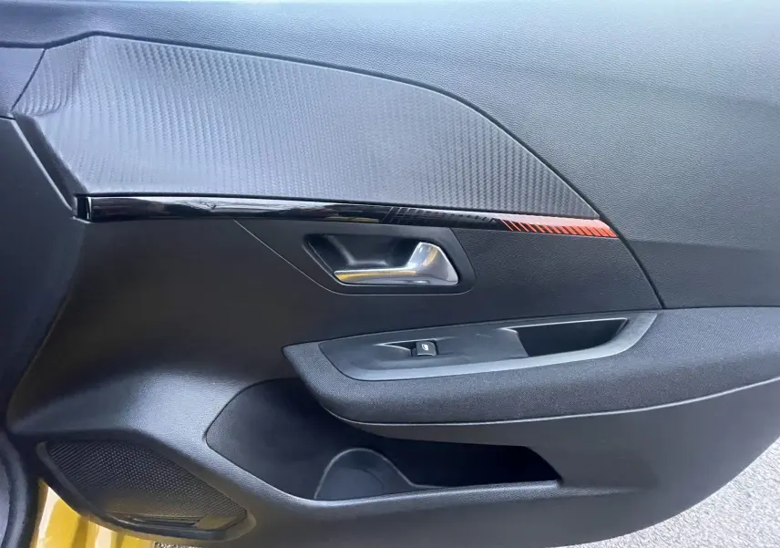 Détail de la porte côté conducteur de la Peugeot 208 II électrique jaune 2023 avec insert décoratif noir et rouge.