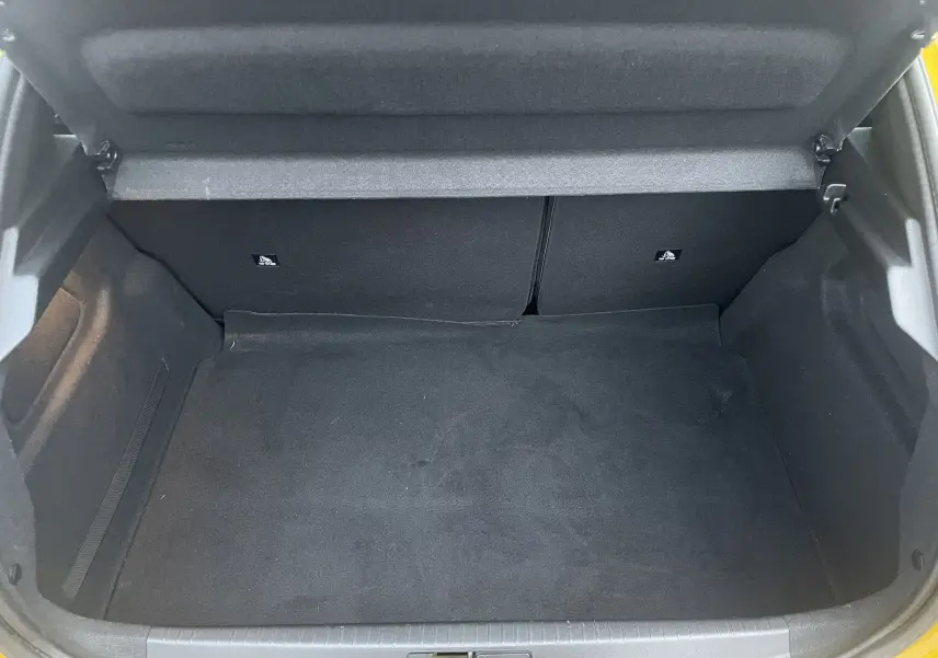 Vue intérieure du coffre spacieux et vide du Peugeot 208 II électrique jaune 2023, avec banquette arrière rabattable.