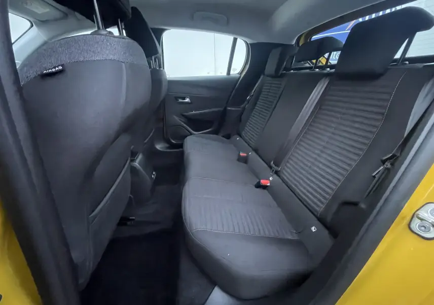 Vue intérieure arrière côté droit de la Peugeot 208 II électrique jaune 2023, montrant les sièges arrière en tissu noir.