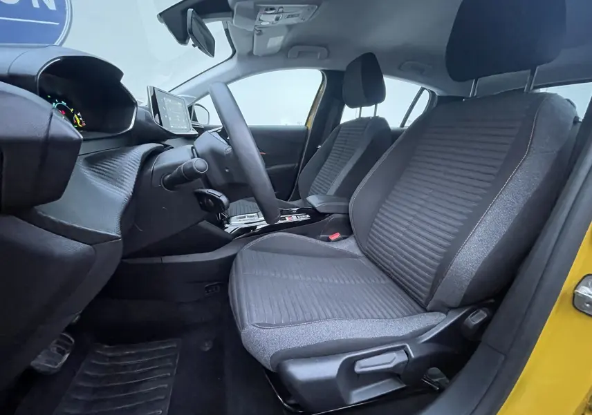 Intérieur avant droit de la Peugeot 208 électrique jaune 2023, avec sièges gris et tableau de bord moderne.