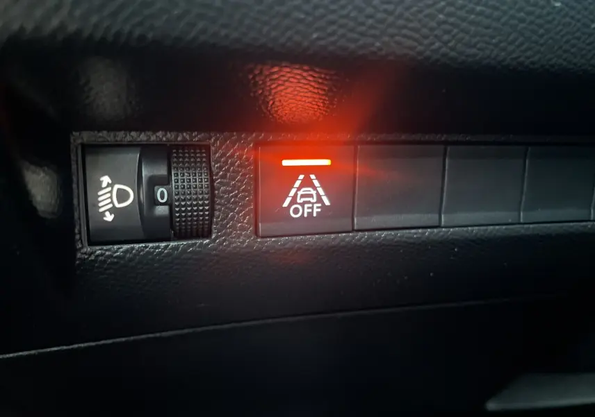 Gros plan sur le tableau de bord du Peugeot 208 II électrique 2023, bouton d'alerte de maintien de voie allumé en rouge.